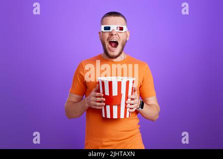Young caucasian man in 3d glasses eating popcorn Stock Photo