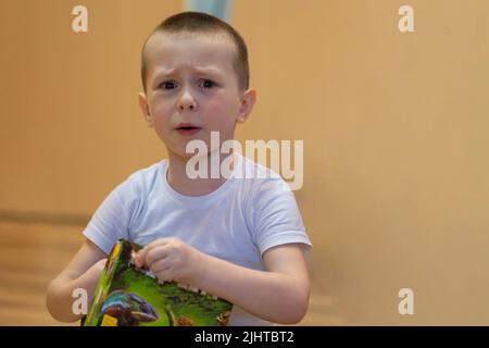 Little boy cries from grief and resentment. He wipes tears from his cheek with his hand. High quality photo Stock Photo