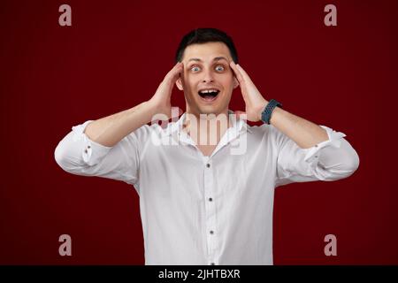surprised young brunette man in white shirt Stock Photo