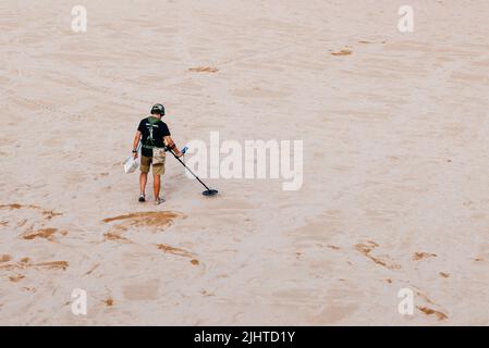 Man with metal detector looking for lost objects on Santa María beach - Luanco beach. Luanco, Gozón, Principality of Asturias, Spain, Europe Stock Photo