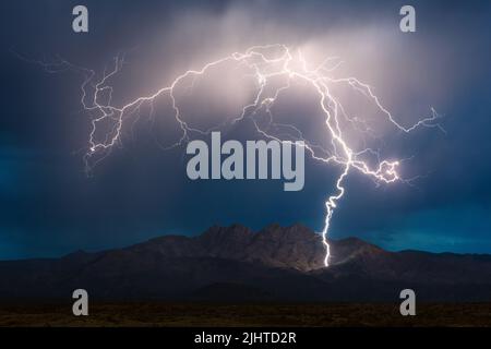 A massive lightning bolt strikes the Four Peaks in the Mazatzal Mountains during a monsoon thunderstorm in Arizona Stock Photo