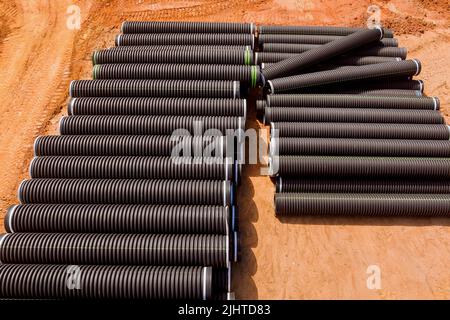 PVC new black plastic pipes stacked in rows at construction site on reconstruction Stock Photo