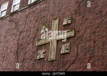 Medieval red brick wall with cement cross. Branches branch over the wall. Stock Photo