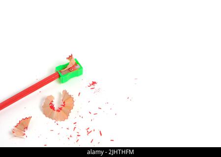 Sharpener and sharpened red pencil with sawdust on white background Stock Photo