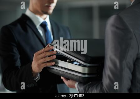 Closeup image of man in black suit opening briefcase with money or documents Stock Photo