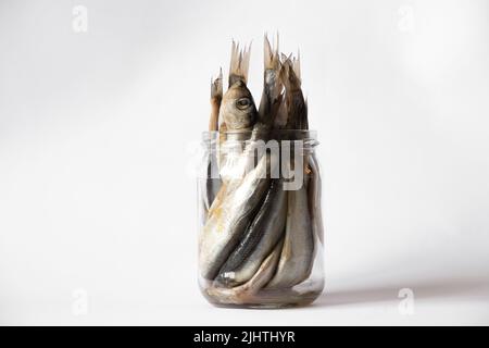salted sprat in a glass transparent jar on a white plate, seafood in a jar, fish on a white plate, sprat Stock Photo