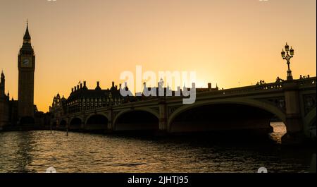 Panorama of anonymous people tourists walking across Westminster Bridge towards The Houses of Parliament and Big Ben at sunset in London, England Stock Photo