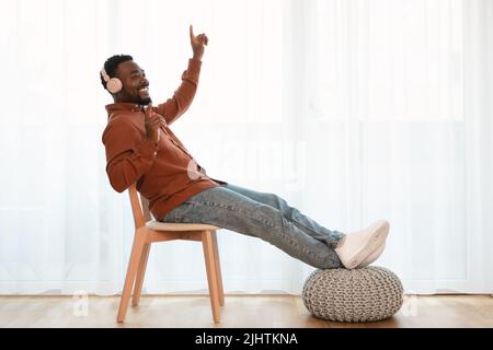 Black Man Wearing Headphones Listening To Music Sitting At Home Stock Photo