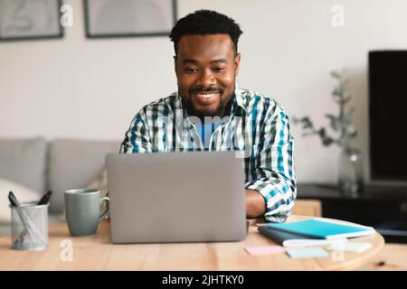 Black Man Using Laptop Working Online Remotely Sitting In Office Stock Photo