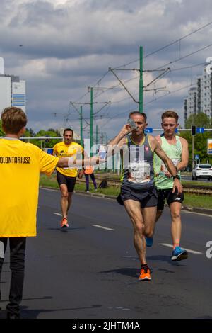 The volunteer offering water to the runners at Wings for Life World Run Stock Photo