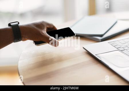 Cropped Shot Of Black Businessman Holding Smartphone Sitting In Office Stock Photo