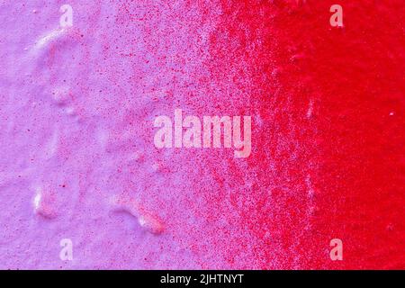 Macro close-up of a spray painted pink and red wall with splashes. Abstract full frame textured splattered graffiti background with copy space. Stock Photo