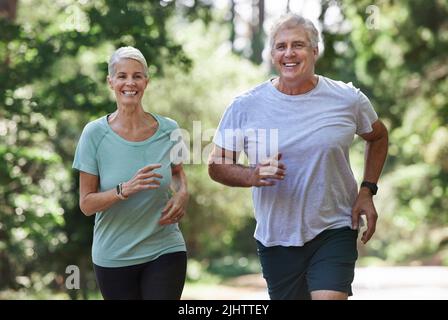 There is no age limit to running. a mature couple running together outdoors. Stock Photo