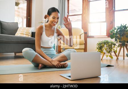 Welcome to another session. a sporty young woman having a video call on a laptop while exercising at home. Stock Photo