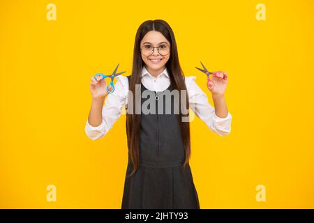 Teenage girl with scissors, isolated on yellow background. Child creativity, arts and crafts. Stock Photo