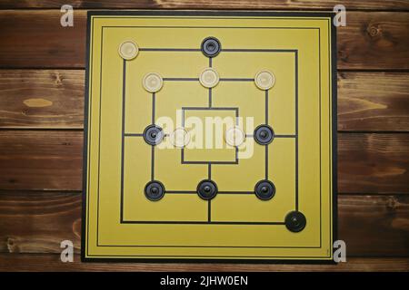 Top down view on gameboard with black and white pieces of strategy game for two people - nine men's morris or mills Stock Photo