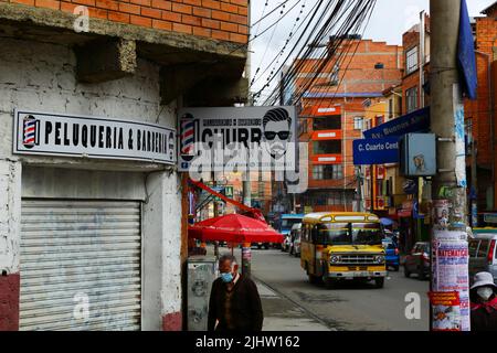 La Paz, Bolivia. An elderly man wearing a facemask (barbijo in Spanish) walking past a closed barber's shop. Stock Photo