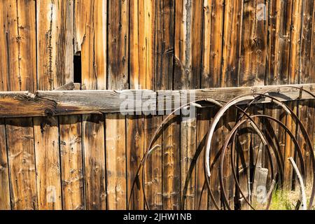 Background of old rusted wagon wheels against a weathered wood barn wall Stock Photo