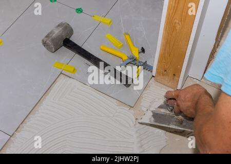 Spreading wet mortar before applying tiles to the bathroom floor puts adhesive Stock Photo