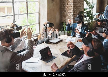 Group of businessperson exploring a virtual project wearing 360 3d vr goggles and sitting around the table - people meets in metaverse reality - busin Stock Photo