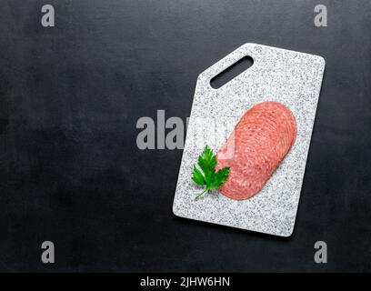 Meat food sausage salami slices on cutting board on black background, mocap. Copy space, flat lay Stock Photo