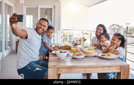 Family and food is so much fun. a young family taking a selfie while having lunch at home. Stock Photo