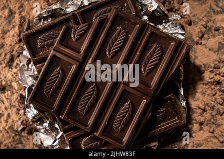 Dark Chocolate in aluminium wrap surrounded by cocoa powder. Stock Photo