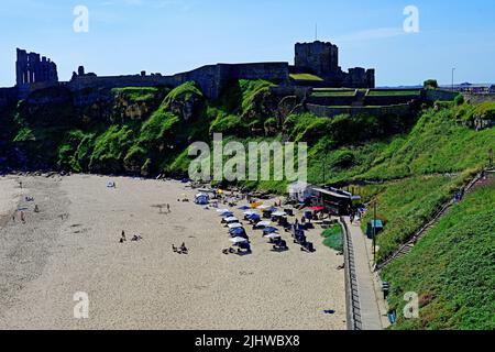 King Edwards Bay beach Tynemouth and Rileys Fish Bar restaurant people bathing swimming having picnics tide out and blue sky view of the ancient Prior Stock Photo