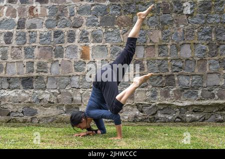 Woman in her 40s practicing yoga in flying crow pose outdoors in the morning Stock Photo