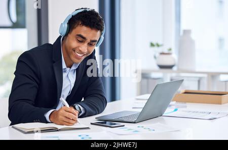 Music keeps me focused while I get all my tasks done. a young businessman wearing headphones while working in an office. Stock Photo