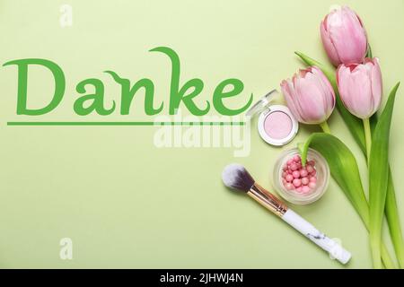 Decorative cosmetics, flowers and word DANKE (German for Thanks) on green background Stock Photo
