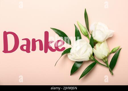 Beautiful flowers and word DANKE (German for Thanks) on pink background Stock Photo