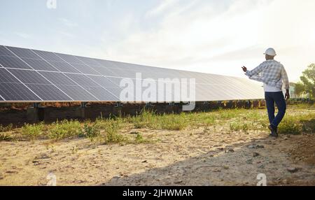 Organically grown veggies always look and taste better. a young man standing next to a solar panel on a farm. Stock Photo