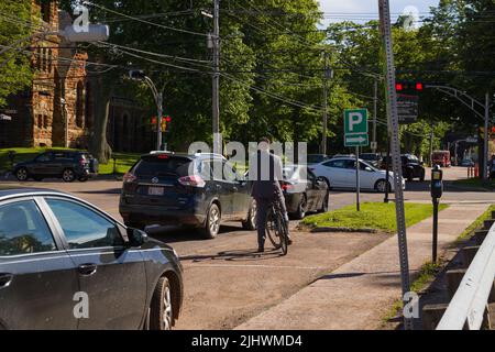 a man in a business suit rides a bicycle. He is late for work. Standing at a traffic light. businessman by bike Stock Photo