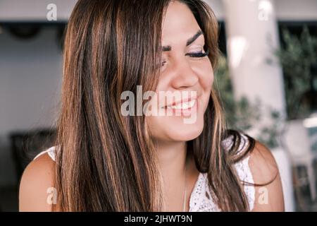 Portrait on the side of a young beautiful smiling tanned brunette with her eyes closed. A happy girl woman enjoys the moment. Joy, pleasure from life Stock Photo
