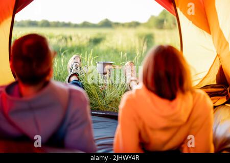 Couple sit in tent and prepare food, close-up on shoes Stock Photo