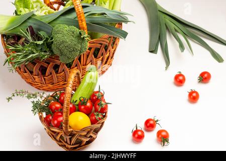 Two wicker baskets with vegetables and greens. Top view. White background. Stock Photo