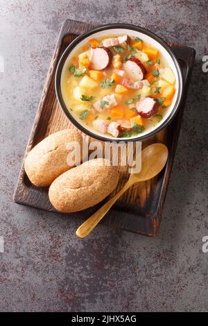 Split pea soup with potato, onion, carrot, bacon and sausages close-up in a bowl on the table. Vertical top view from above Stock Photo