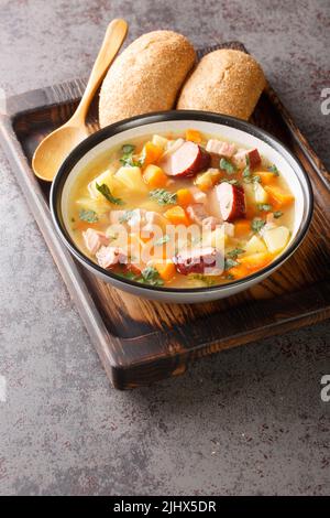 Split pea soup with potato, onion, carrot, bacon and sausages close-up in a bowl on the table. Vertical Stock Photo