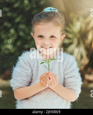 Love, honesty, and connection are cultivated in a family. a little girl holding a plant outside. Stock Photo
