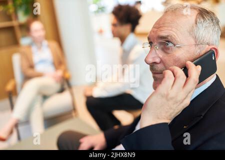 Senior businessman or consultant talking on smartphone in meeting in office Stock Photo