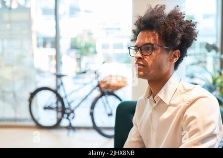 Thoughtful young start-up founder with afro hairstyle in his agency office Stock Photo
