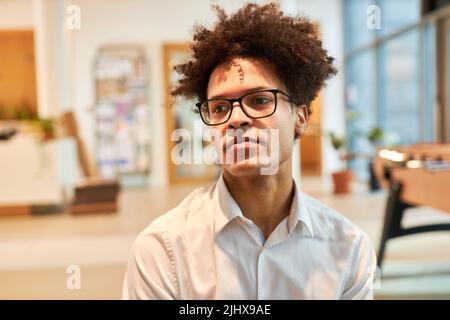 Pensive or dreamy young man as a startup founder in his agency Stock Photo