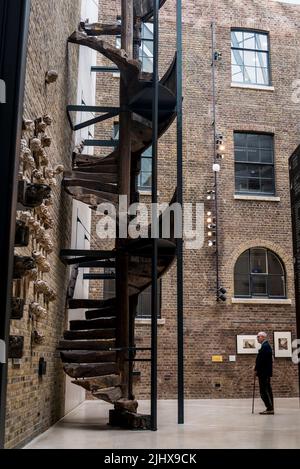 Visitor looking at the Medieval wooden staircase and sculptures on the wall,  V&A, London, UK Stock Photo