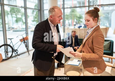 Elderly business man and colleague with documents in the office discuss a project Stock Photo