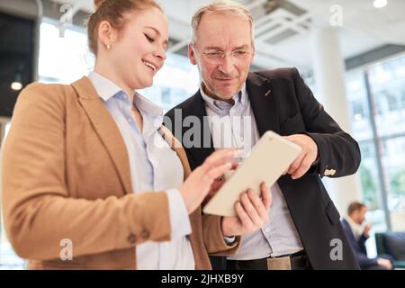 Young business woman and senior manager reading business news on tablet pc in office Stock Photo