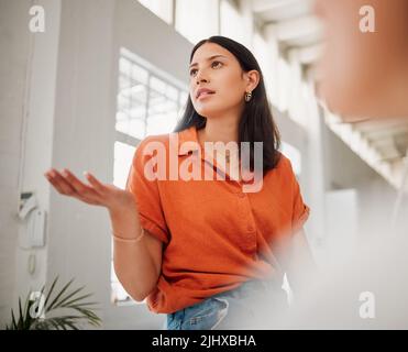 Young hispanic business woman from below speaking to colleagues during a meeting in an office boardroom. Woman asking a question, sharing feedback and Stock Photo