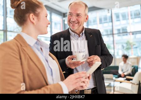 Senior businessman and young female colleague using tablet computer during coffee break in office Stock Photo