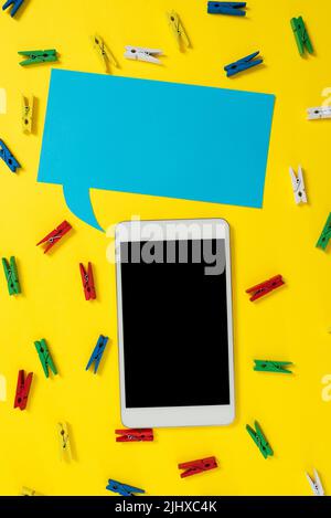 Pegs Placed Around Tablet And Speech Bubble With Important Informations. Colorful Pins Arranged All Over Dialogue Balloon And Phone Screen With Stock Photo