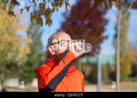 Side view of senior man resting and drinking water after workout while looking away Stock Photo